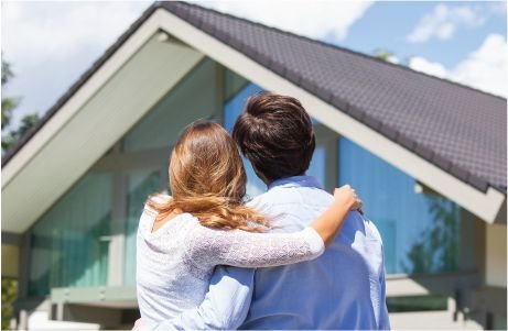 Una pareja está de pie, admirando una casa.