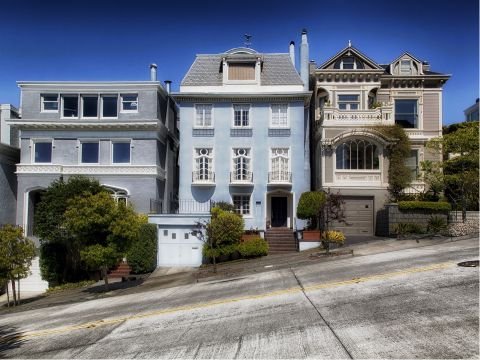 Three elegant Victorian-style houses on a steep hill.