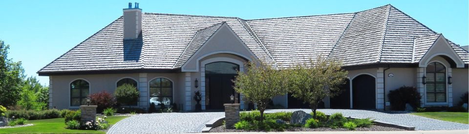 Single story house with arched windows and stone driveway.