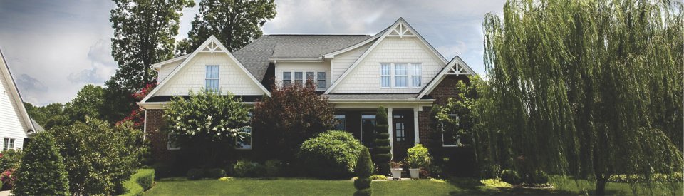 A charming suburban house with a gray roof and white facade.